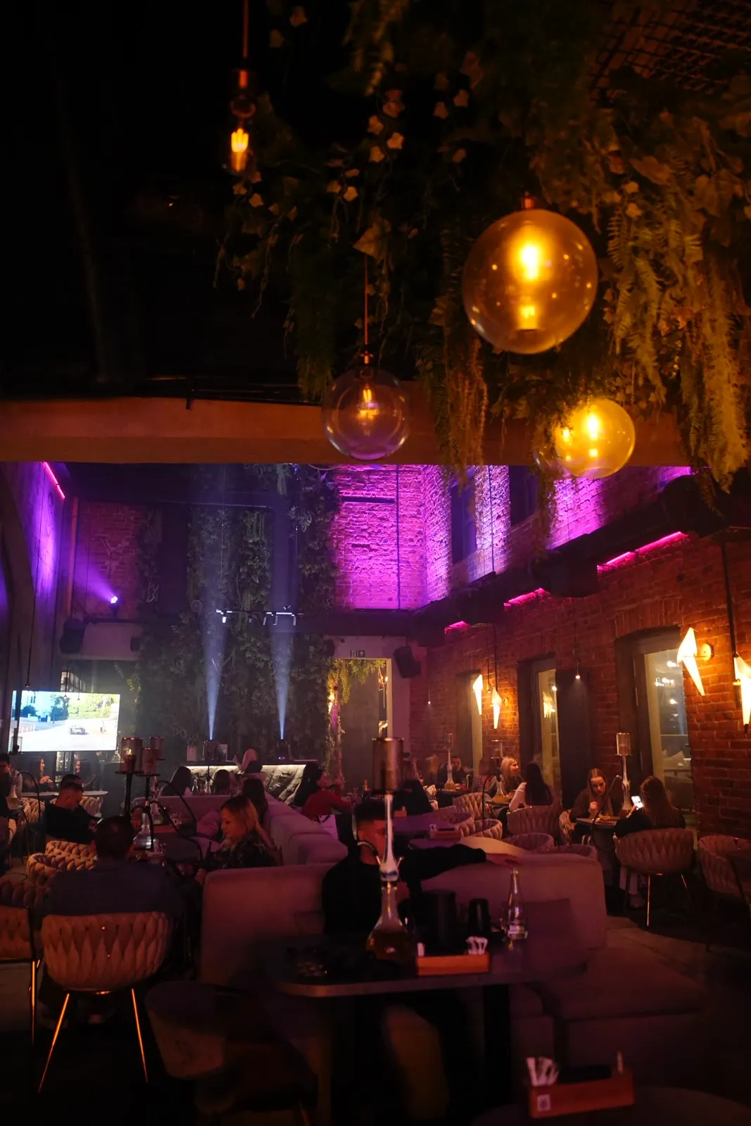 The Selection lounge with hanging greenery and warm light in a historic mill
